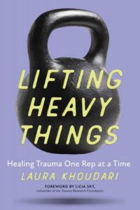 Kettlebells book cover: "Lifting Heavy Things: Healing Trauma One Rep At A Time" by Laura Khoudari, appears in yellow text overlaid on top of a floating kettlebell.
